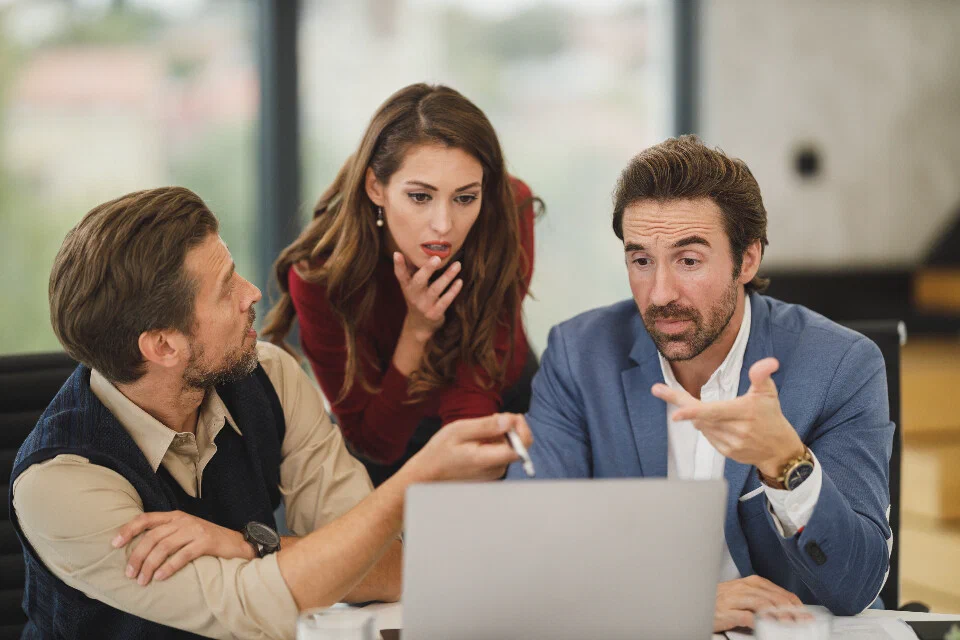 A consultant walking two colleagues through findings on a laptop