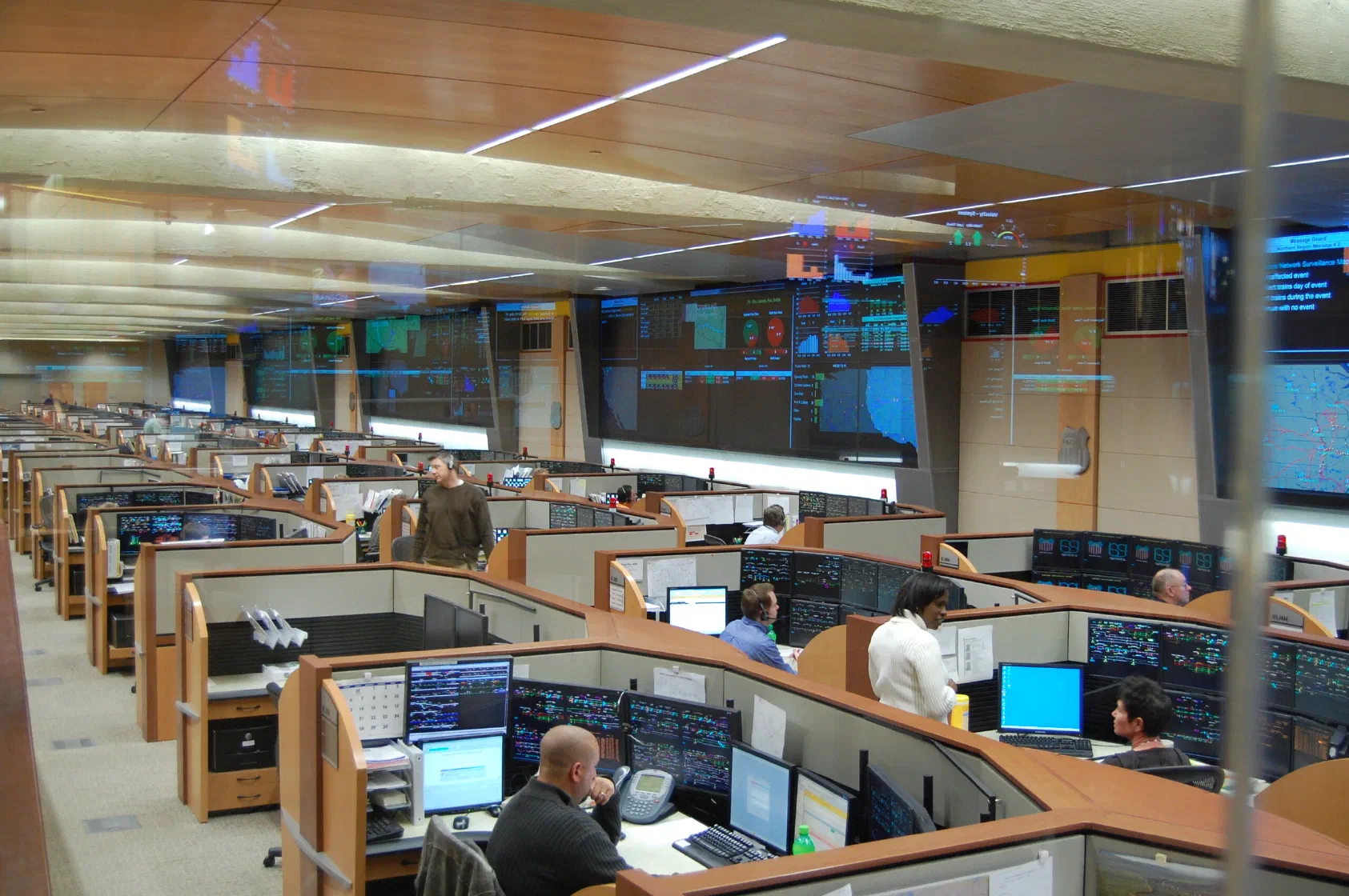 Operators at rows of multi-monitor workstations in a large operations center